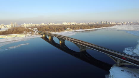 Luftbild-Autobrücke-über-Gefrorenen-Fluss-In-Der-Winterstadt.-U-Bahnen-Im-Freien
