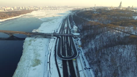 Aerial-view-car-driving-on-highway-junction-in-winter-city.-Snowy-city-landscape