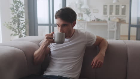 Serious-freelancer-relaxing-with-cup-of-tea-at-home.-Handsome-man-drinking-tea.