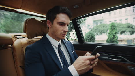 Annoyed-business-man-typing-message-in-cellphone-car.-Male-ceo-working-in-car.