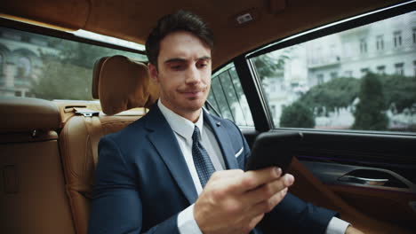 Upset-male-professional-reading-bad-news-on-smartphone-in-salon-of-business-car.
