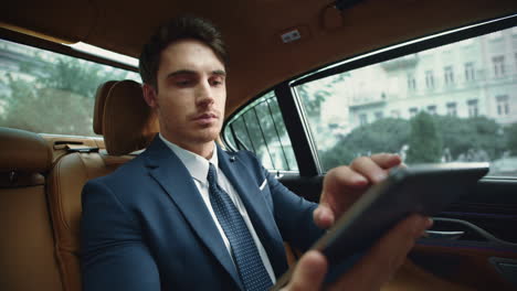 Portrait-of-focused-business-man-working-on-tablet-computer-in-business-car.