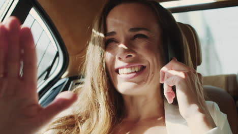 Smiling-business-woman-rejoicing-at-good-news-on-smartphone-in-business-car.