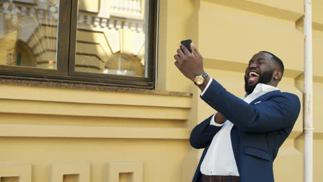 Afro-business-man-having-video-call-outdoor.-Afro-guy-making-gestures-with-phone