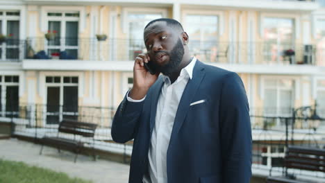 African-american-businessman-standing-with-phone-outside.-Afro-man-talking-phone