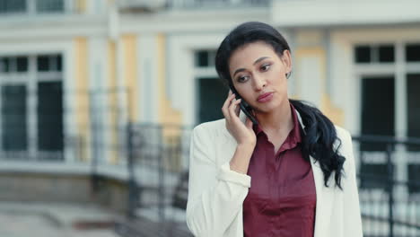 Calm-businesswoman-talking-phone-outdoors.-Focused-lady-using-smartphone
