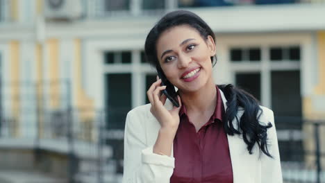 Laughing-businesswoman-speaking-phone-outside.-Mixed-race-lady-talking-outdoors
