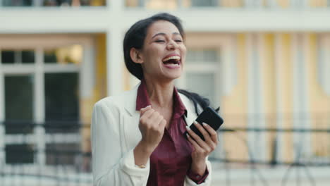 Laughing-mixed-race-woman-receiving-good-news.-Businesswoman-celebrating-victory