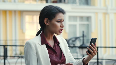 Disappointed-female-entrepreneur-having-video-chat-on-mobile-phone-at-street.