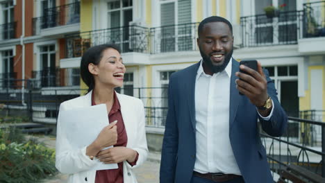Businessman-and-businesswoman-walking-outdoors.-Couple-having-video-chat-outside