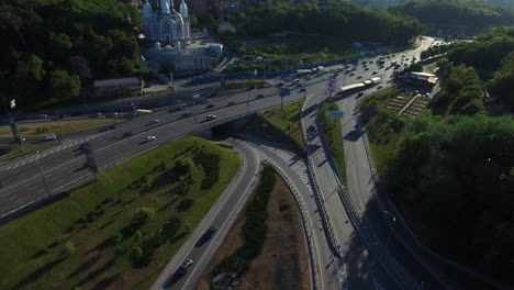 Car-moving-past-church-in-city.-Aerial-view-car-traffic-on-highway-interchange