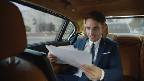 Smiling-male-professional-rejoicing-at-good-record-in-paperwork-in-business-car.