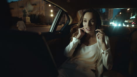 Smiling-business-lady-flirting-on-smartphone-in-dark-salon-of-business-car.