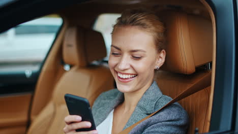 Closeup-businesswoman-using-phone-at-car.-Woman-driver-smiling-on-front-seat