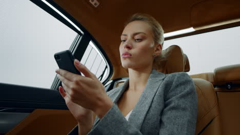 Portrait-woman-sitting-with-phone-backseat.-Female-using-smartphone-at-car