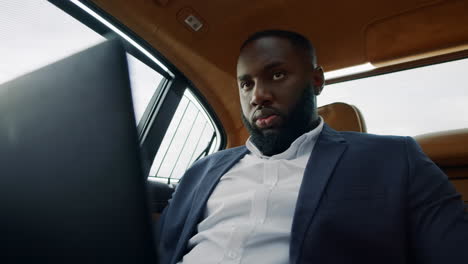 African-man-looking-laptop-screen.-Businessman-working-computer-at-car