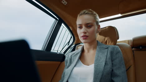 Surprised-business-woman-using-laptop-at-backseat.-Businesswoman-smiling-at-car
