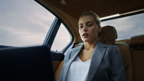 Focused-business-woman-having-video-call-at-backseat.-Girl-waving-hand-in-car.