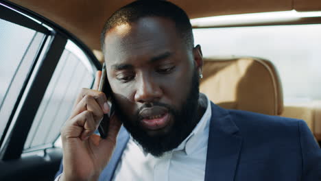 Nahaufnahme-Fokussierter-Afrikanischer-Geschäftsmann,-Der-Mit-Dem-Mobiltelefon-In-Einem-Luxusauto-Spricht.