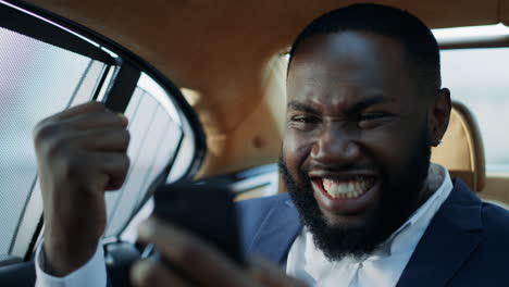 Portrait-of-winner-african-man-business-celebrating-victory-at-luxury-car.