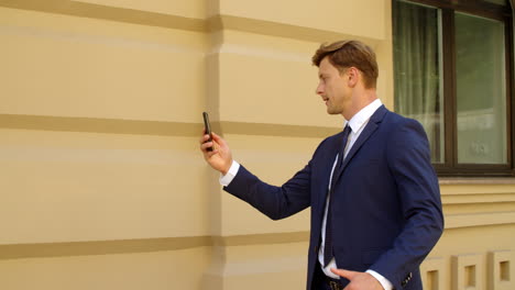 Aggressive-businessman-having-video-call-online-on-mobile-phone-outdoors