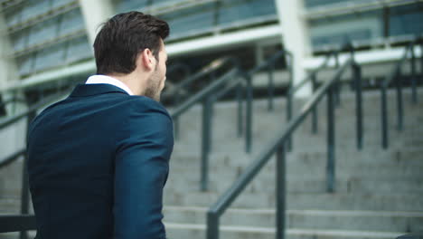 Portrait-businessman-walking-upstairs-near-stadium.-Man-looking-away-outdoors