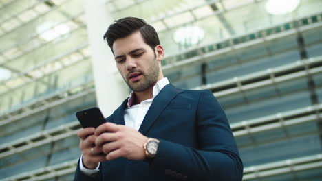 Portrait-businessman-using-smartphone.-Man-standing-with-phone-in-hand-outdoors