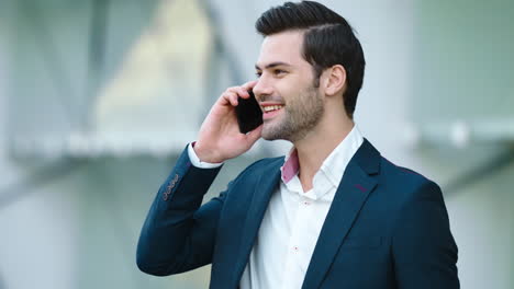Portrait-businessman-using-smartphone.-Man-smiling-with-phone-in-hand-outdoors