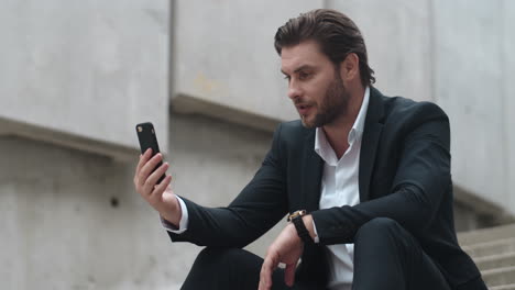 Businessman-having-video-chat-on-mobile-phone.Entrepreneur-waving-hand-at-camera