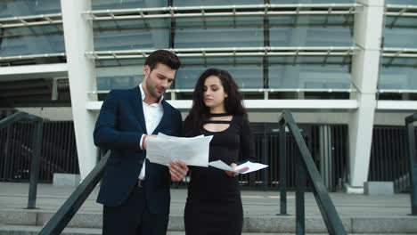 Closeup-couple-discussing-documents-near-stadium.-Couple-discussing-project