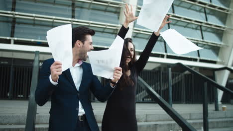 Couple-throwing-papers-in-slow-motion.-Couple-laughing-together-near-stadium