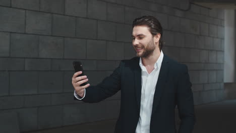 business-man-waving-hand-at-camera-on-street.-Entrepreneur-talking-on-video-chat