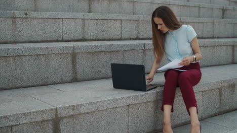 Businesswoman-typing-on-laptop-in-city.-Manager-working-with-financial-documents