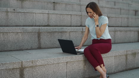 Business-woman-talking-on-smartphone-outdoors.-Woman-working-on-laptop