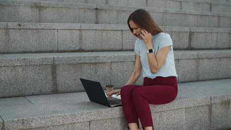 Businesswoman-talking-on-smartphone-outdoors.-Woman-working-on-laptop