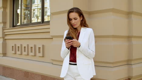 Thinking-business-woman-texting-message-on-mobile-phone-outdoors