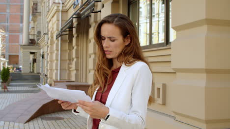 Upset-business-woman-reading-documents-outdoors.-Sad-businesswoman
