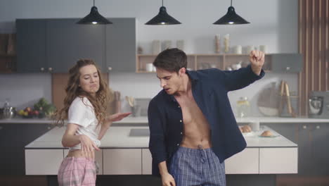 Happy-couple-dancing-together-at-kitchen-background.-Excited-friends-moving-body