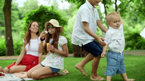 Boys-and-girl-playing-in-forest.-Laughing-parents-relaxing-with-children-in-park