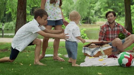 Happy-siblings-playing-in-park.-Young-family-having-picnic-outdoors.