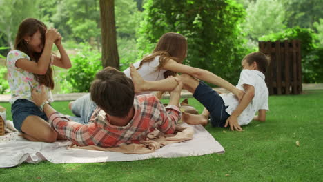 Parents-playing-with-children-in-park.-Kids-and-parents-lying-on-blanket
