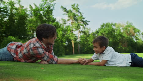 Boy-and-man-armwrestling-on-grass.-Father-and-son-practising-arm-wrestling
