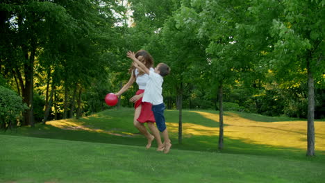 Mother-and-children-playing-with-ball-in-meadow.-Family-enjoying-time-outside