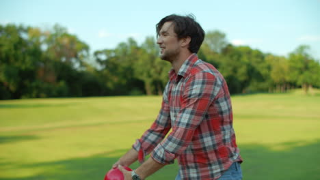 Man-holding-ball-in-hands-outside.-Smiling-guy-talking-with-somebody-in-park
