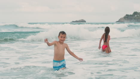 Joyful-children-having-fun-at-coastline.-Happy-boy-dancing-in-sea-surf.