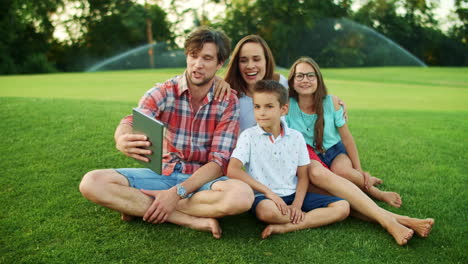 Family-having-conversation-by-video-chat-on-pad-in-park.-Family-using-tablet