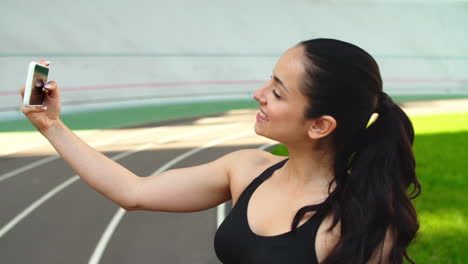 Mujer-Deportiva-Tomando-Una-Foto-Selfie-En-Un-Teléfono-Móvil-En-La-Pista-Del-Estadio