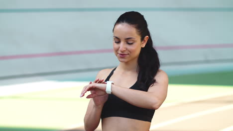 Portrait-of-fitness-woman-checking-results-at-smart-watch-at-sport-stadium
