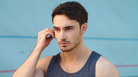 Portrait-of-fitness-man-wearing-earphones-on-modern-track