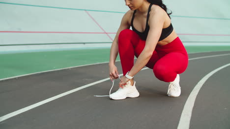 Woman-runner-preparing-for-workout-on-track.-Fitness-girl-tying-up-shoes-outdoor